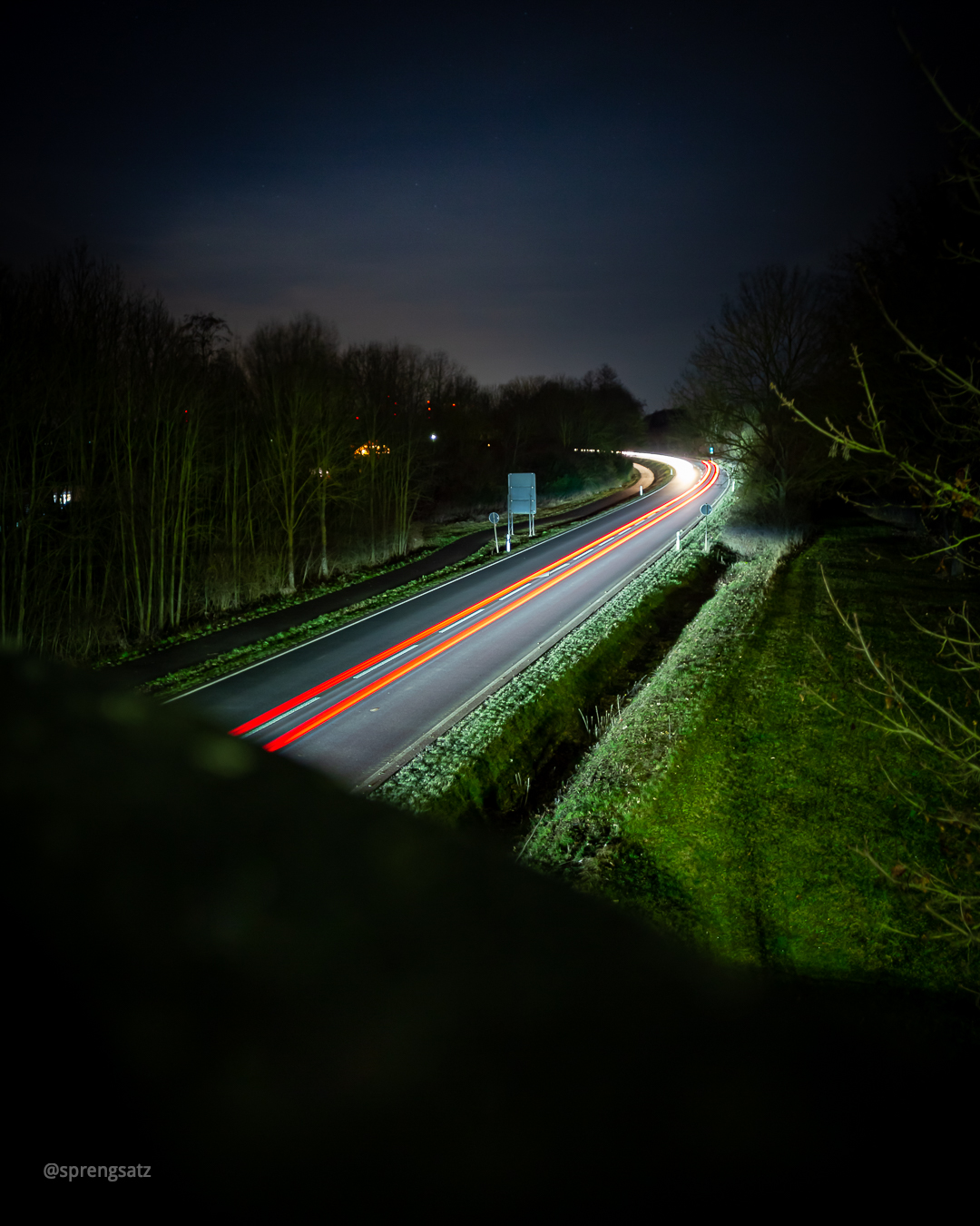 Landstraße bei Nacht mit Lichtspuren von Autolichtern