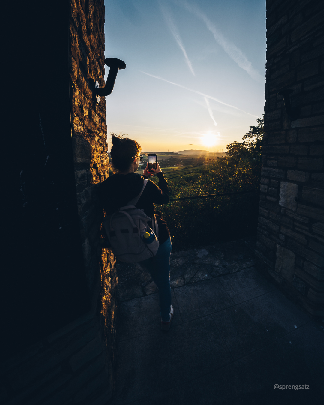 Frau fotografiert mit ihrem Smartphone den Sonnenuntergang am Zellertaler Ehrenmal (RLP)